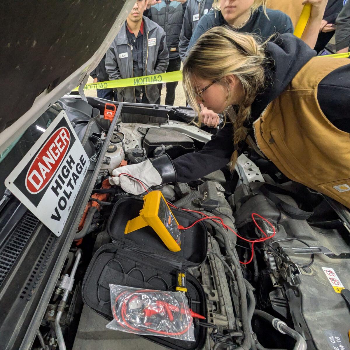 Female student checking the voltage on a hybrid